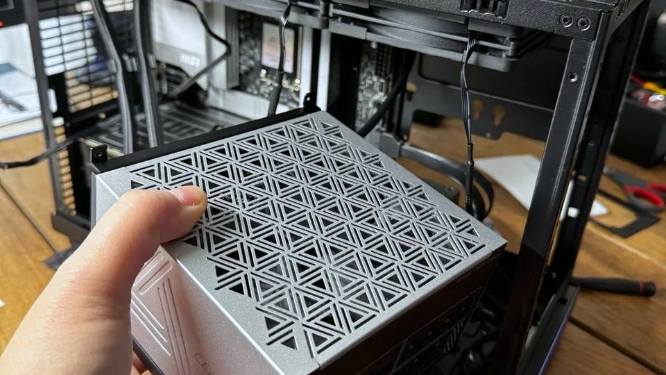 Adrian Barkus building a Centurion machine — fitting the power supply into an open case on a workbench.